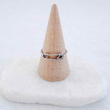 A clip ring with gold plated design displayed on a beige conical stand.