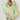 Woman wearing Matera Sarong in yellow and green abstract print, draped as a beach wrap.