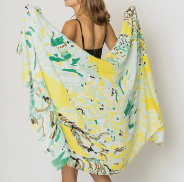 Woman wearing Matera Sarong in yellow and green abstract print, draped as a beach wrap.