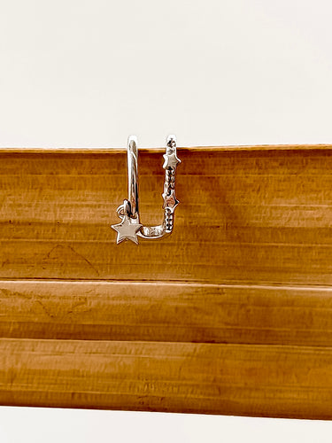 A gold-plated ear cuff with a star design displayed on a wooden surface.