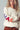 Person wearing a cream sweater with colorful letters on a plain background