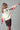 Model wearing ivory knit sweater with colorful MERRY CHRISTMAS lettering on sleeves and back.