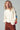 Woman wearing a white sweater with colorful letter sleeves against a gray background
