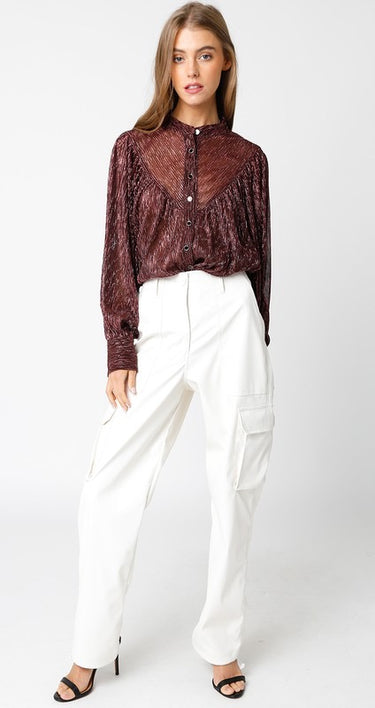 Woman wearing a patterned blouse and white pants on a white background