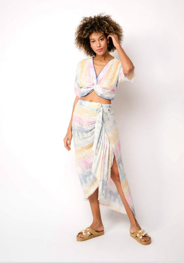 Woman wearing a pastel twist-front crop top in soft sunset tones — lightweight resort style by Matte.