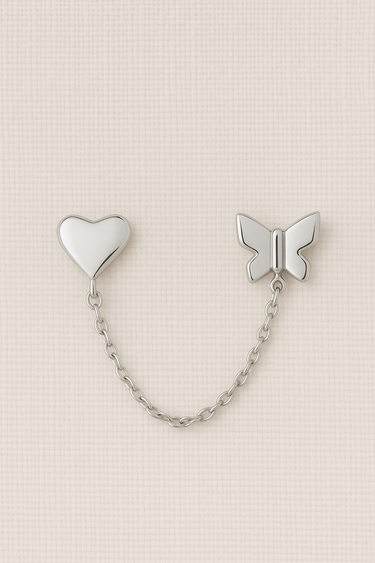 Silver chain stud earrings featuring heart and butterfly design on a neutral beige background – Noelle Stud Chain Earrings by Matte