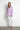 Model styled in Noema Lilac Shirt with white jeans and nude heels.