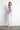 Model wearing Noema Lilac Shirt in lilac cotton, side profile with white jeans.