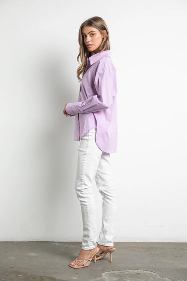 Model wearing Noema Lilac Shirt in lilac cotton, side profile with white jeans.