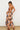Otti Maxi Dress strapless leaf print maxi dress angled side pose showing drape and movement.