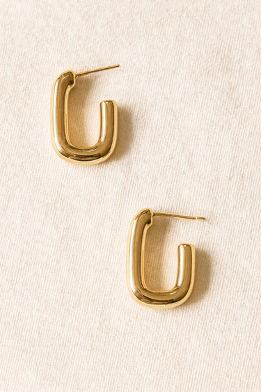 Pill Link Stud Earrings — gold-plated pill-shaped link earrings with high-polish mirror finish on beige linen background, sculptural and bold by Matte.