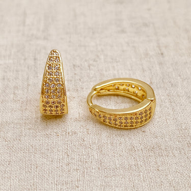 Poli Huggie Earrings, gold huggie hoop earrings with tapered pavé-set design and polished mirror finish, photographed on white linen background with soft editorial lighting.