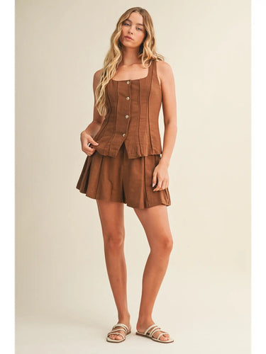 Ragit Short brown high-waisted pleated shorts full body front view, showing tailored silhouette, structured waistband, and lightweight summer fabric.