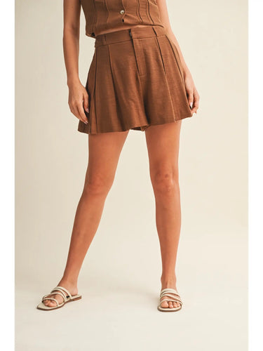 Ragit Short brown high-waisted pleated shorts full body front view, showing tailored silhouette, structured waistband, and lightweight summer fabric.