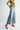 Person wearing a yellow top and light blue wide-leg jeans on a white background