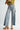 Person wearing light blue jeans and a yellow top on a white background