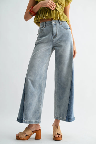 Person wearing light blue jeans and a yellow top on a white background