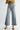 Person wearing light blue wide-leg jeans on a white background