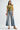 Woman wearing a green ruffled top and blue jeans on a white background