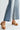 Person wearing denim wide-leg pants and tan woven sandals on a white background