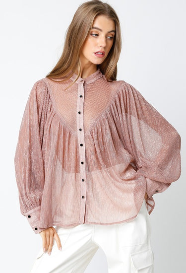 Model wearing Selene Metallic Blouse in rose metallic pleated fabric with button-down closure and long sleeves.
