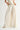 Rumi Pant cream high-rise wide-leg trousers front view showing soft tailored pleats, fluid drape, and elongated silhouette styled with a light fitted top.