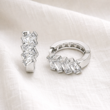 Satori Huggie Earrings – huggie earrings with clear crystal stone detailing, photographed on a soft neutral fabric background.