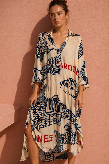 Seaside Dress shown on model, featuring a relaxed flowy silhouette, short sleeves, and bold coastal-inspired print in neutral and navy tones