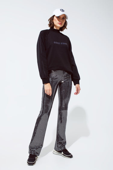Shimmering black sequin flare pants styled with a casual sweatshirt, statement night-out look by Matte