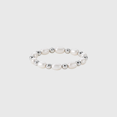 A gold-filled stretch ring with polished silver beads and pearls displayed on silver backdrop