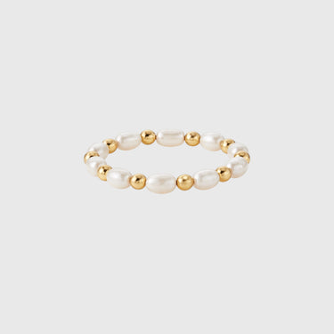 A gold-filled stretch ring with polished gold beads and pearls displayed on silver backdrop