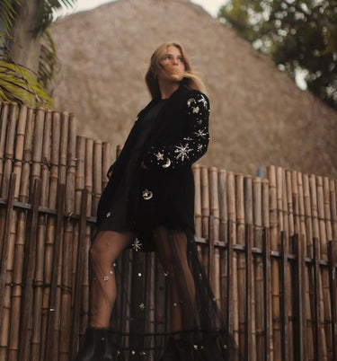 Woman wearing black velvet Starry Night Jacket with embroidered silver stars, standing outdoors.