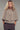 Model wearing neutral knit cape cardigan with oversized buttons and textured fabric, front view.