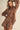 Woman wearing a brown embroidered outfit on a beige background