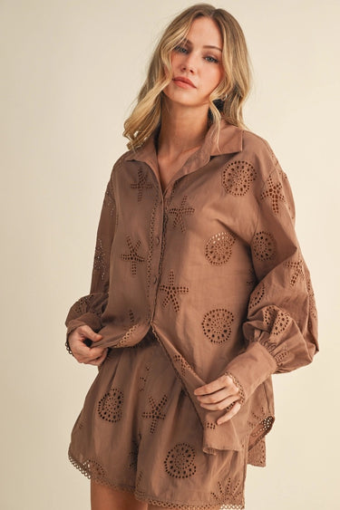 Woman wearing a brown embroidered dress against a plain background
