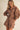 Woman wearing a brown outfit with cut-out designs on a beige background