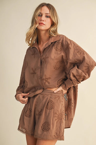 Woman wearing a brown embroidered outfit on a beige background