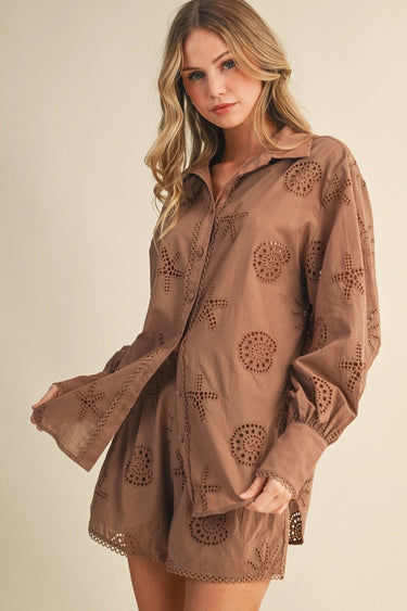 Woman wearing a brown lace shirt against a plain background