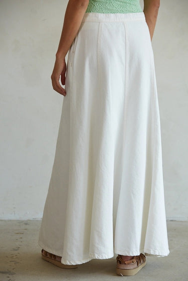 Person wearing a long white skirt with a plain background