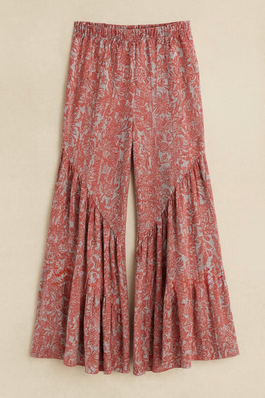 Pink and purple bohemian printed wide-leg pants with flared tiered hem and elastic waist — resort look.
