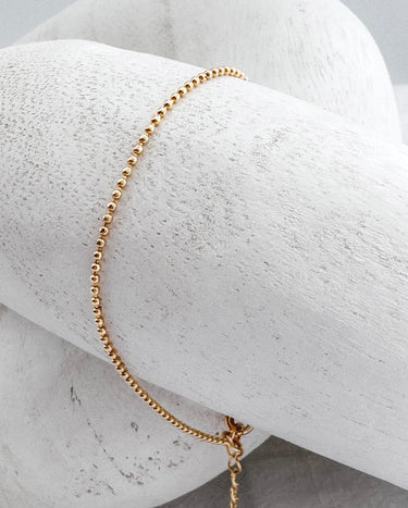 Gold plated beaded bracelet on white marble background – Atina Bracelet