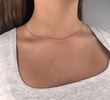 Vitoria Necklace close-up showing a minimalist fine gold chain necklace on the neckline