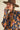 Close-up of model wearing navy knit sweater with bold orange and pink floral knit design.