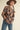 Side view of model wearing navy floral knit sweater with orange and pink floral design, relaxed oversized fit.