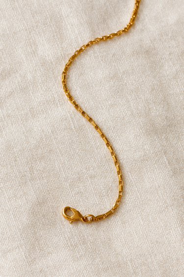Zen Bracelet — gold-plated box chain bracelet with lobster clasp, polished mirror finish, photographed on beige linen background, Matte Jewelry Collection.