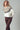 Model wearing Zermatt Sweater, fair isle knit pullover in cream with taupe and brown pattern, styled with brown pants.