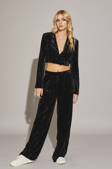 A female model wearing a black Akima pant with a high waist and relaxed fit. The model is paired with a cropped top and white sneakers, standing against a neutral background.