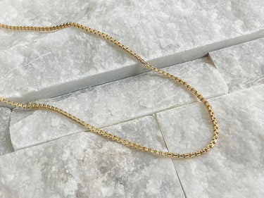 Albacete Necklace by Matte, gold plated chain necklace displayed on marble tile background