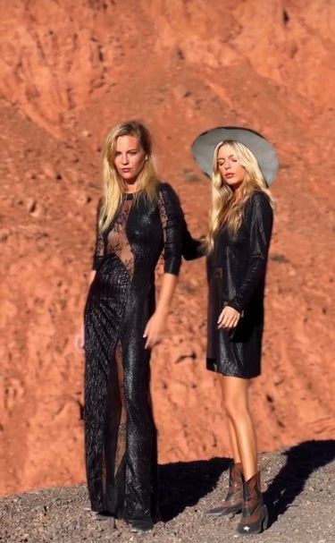 Woman wearing Ammica Maxi Dress in black sheer fabric, styled against desert backdrop.