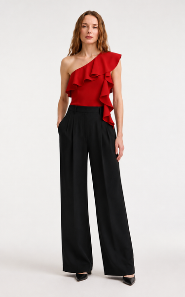 Woman wearing the Anisa red one-shoulder ruffle top with black wide-leg trousers, front view.